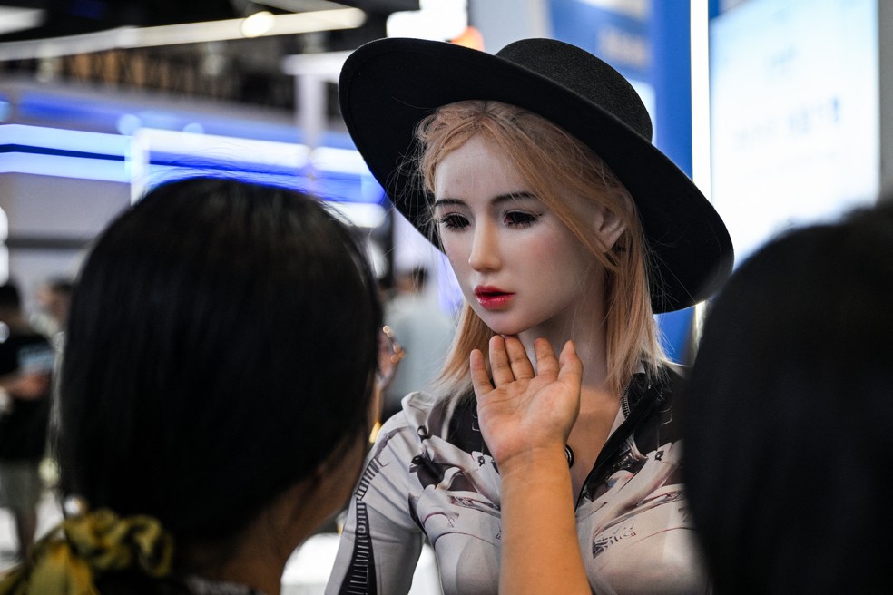 Uma mulher toca em um robô humanoide durante a Conferência Mundial de Inteligência Artificial (WAIC) — Foto: Hector RETAMAL / AFP