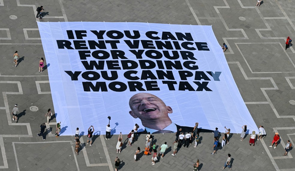 Manifestantes protestam contra o casamento de Jeff Bezos em Veneza com faixa que diz: "se você pode alugar Veneza para o seu casamento， você pode pagar mais impostos" — Foto: Stefano Rellandini/AFP